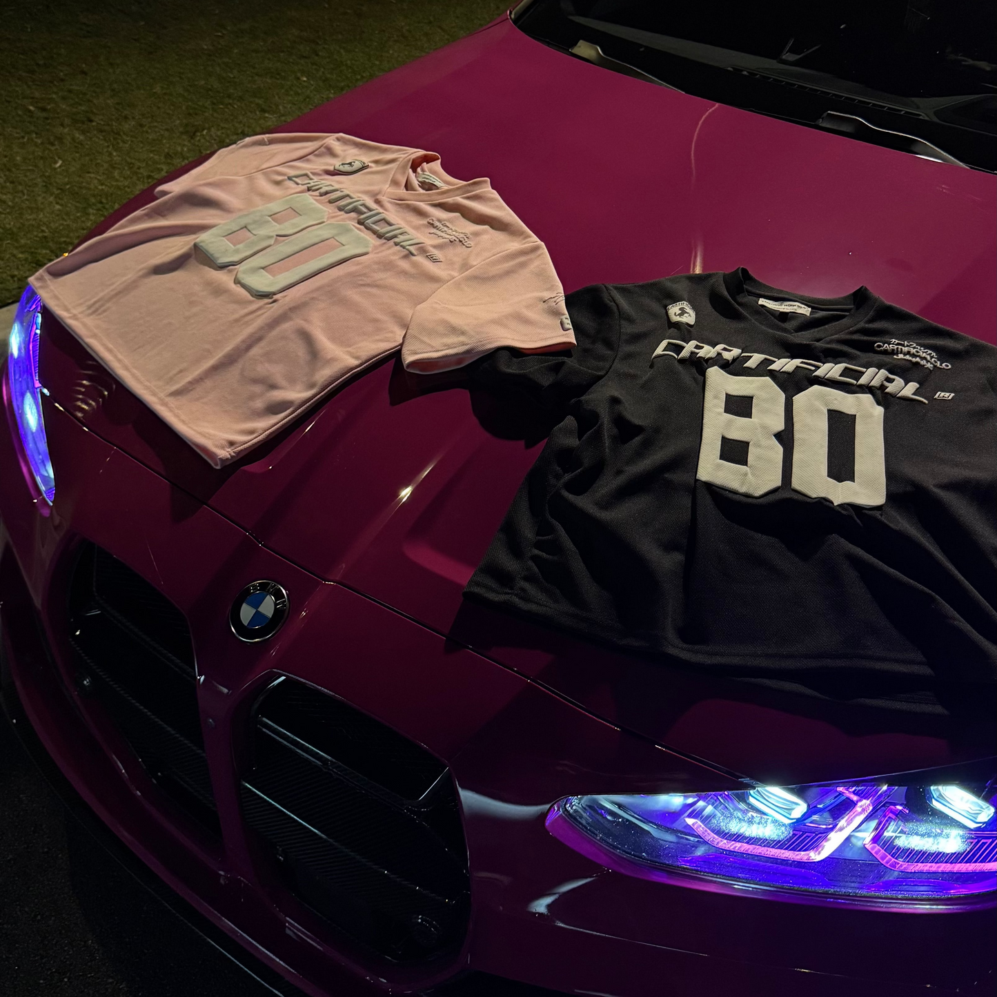 Two t-shirts on a car hood with a dark background