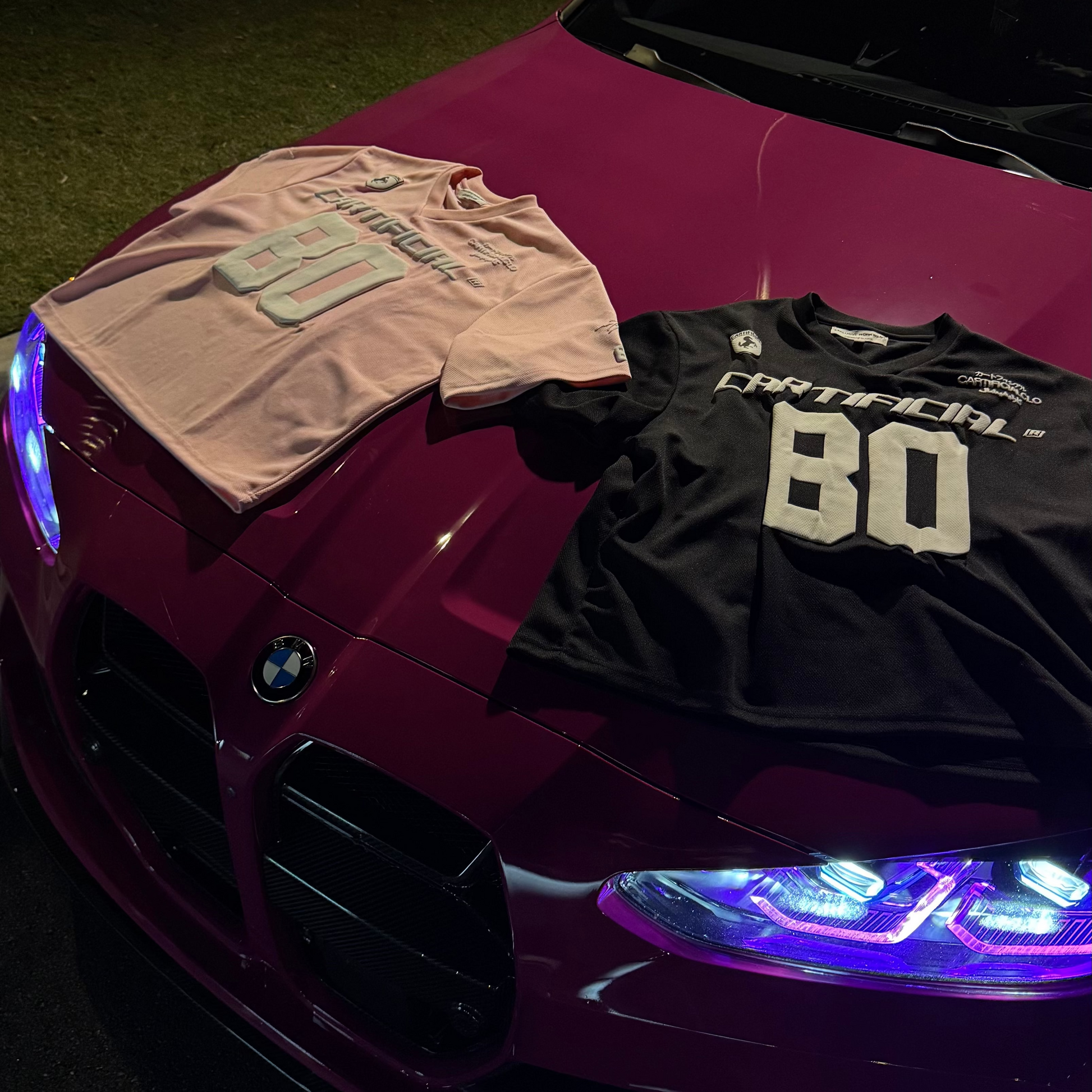 Two t-shirts on a car hood with a dark background